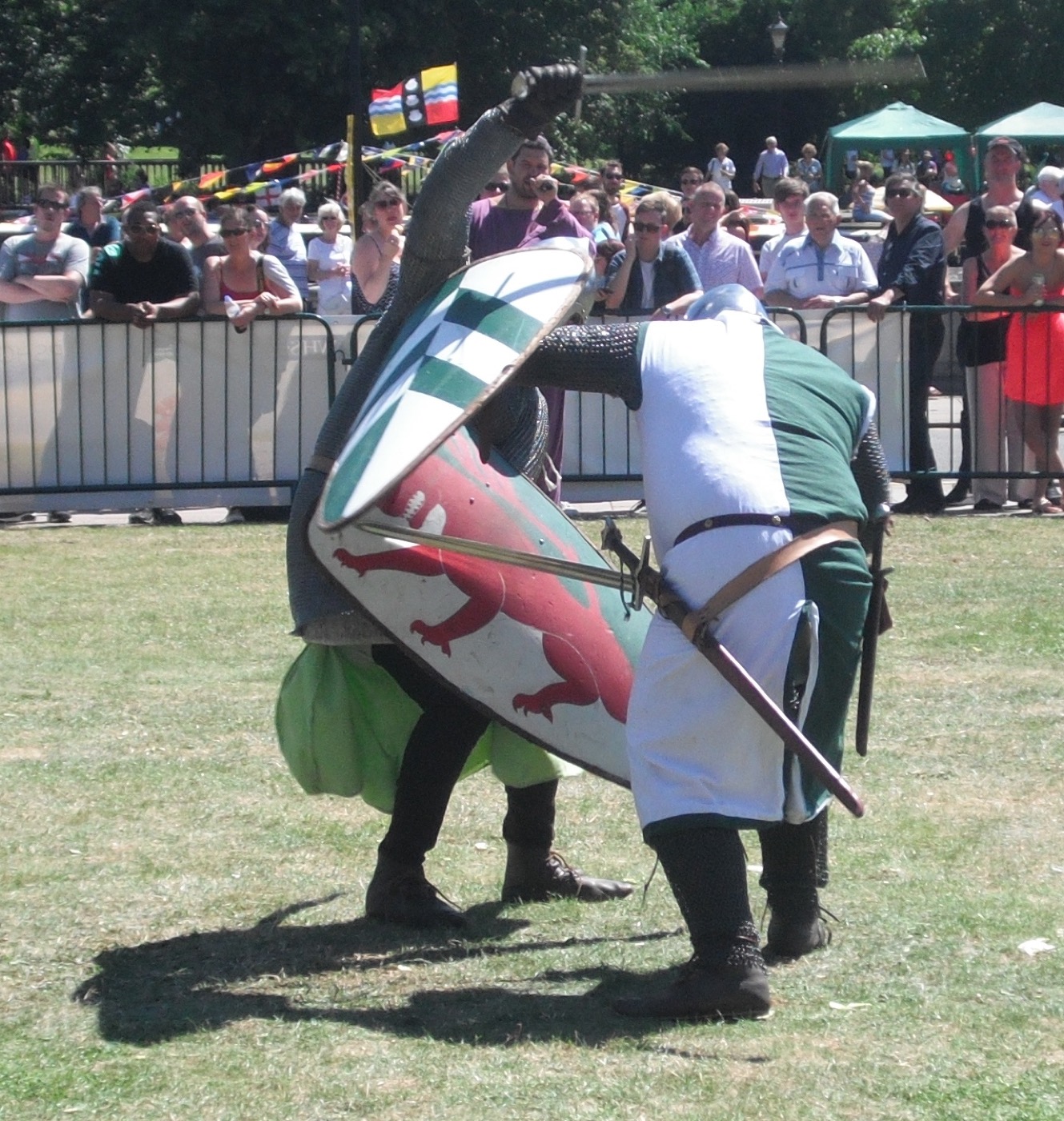 Recreadores medievales combatiendo con espada y escudo durante un torneo de recreación histórica
